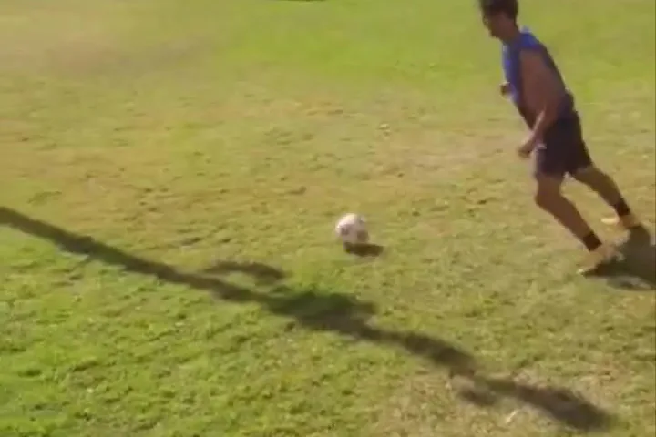 Jogador chutando a bola em campo de grama natural durante a tarde